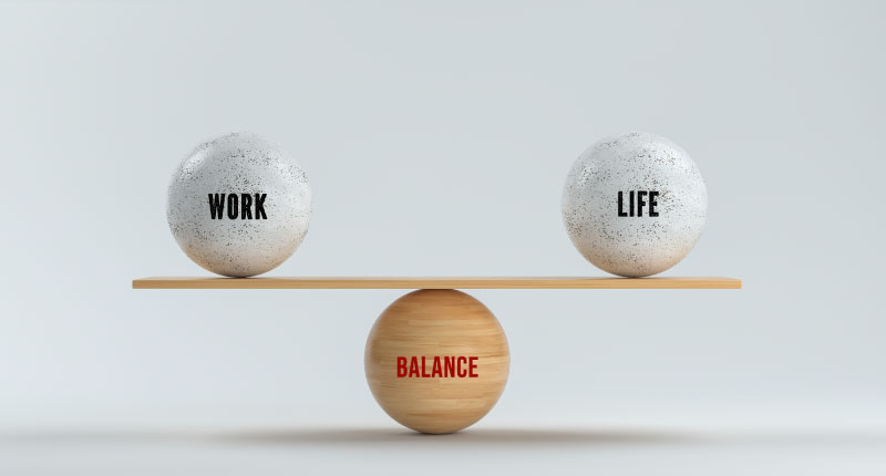 Spheres balanced on a scale with the words work, life and balance