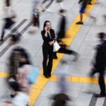 A Japanese woman talking on a mobile phone surrounded by commuters in an open area